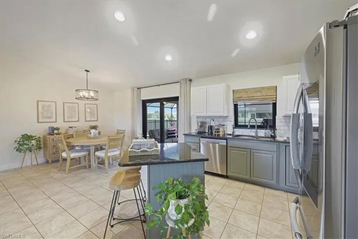 Kitchen featuring appliances with stainless steel finishes, decorative backsplash, light tile patterned flooring, a center island, and a kitchen bar