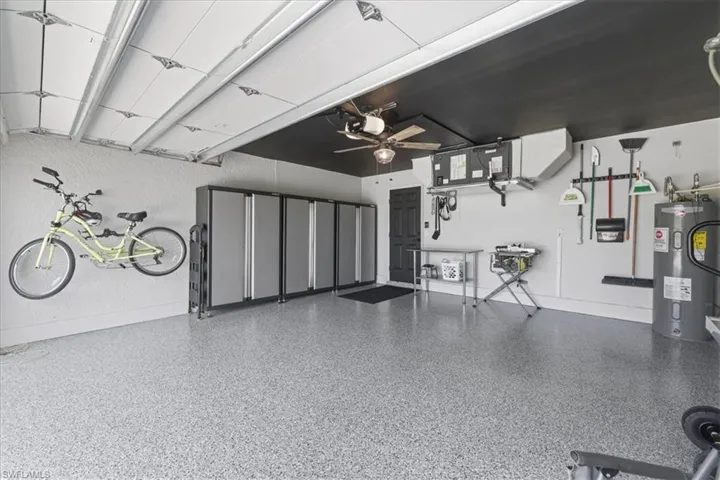 Garage with water heater, a ceiling fan, and a textured wall