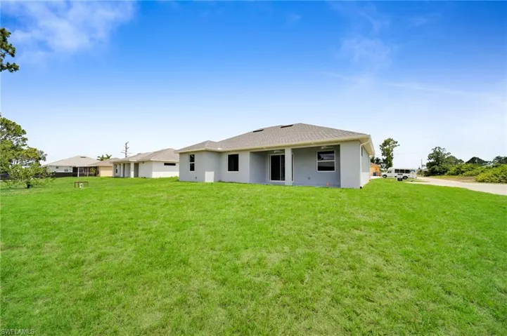 Rear view of house with a lawn and stucco siding