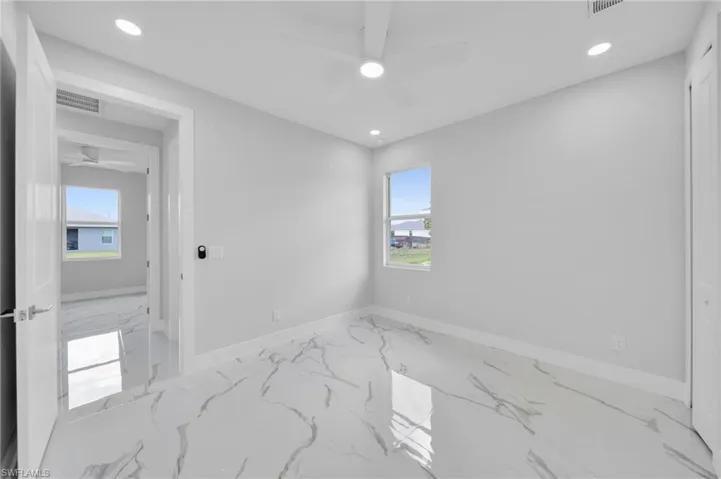 Empty room with a ceiling fan, marble finish floors, healthy amount of natural light, baseboards, and recessed lighting