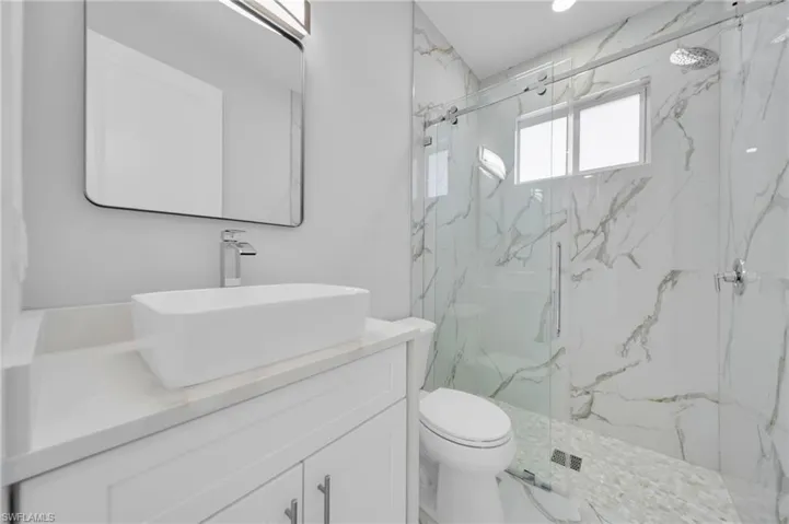 Full bathroom featuring vanity, a marble finish shower, and toilet