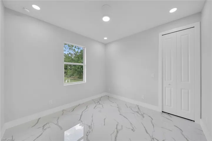 Empty room featuring baseboards, marble finish floors, recessed lighting, and a smoke detector