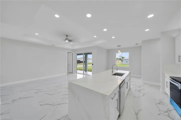 Kitchen featuring a sink, a raised ceiling, recessed lighting, baseboards, and stainless steel appliances