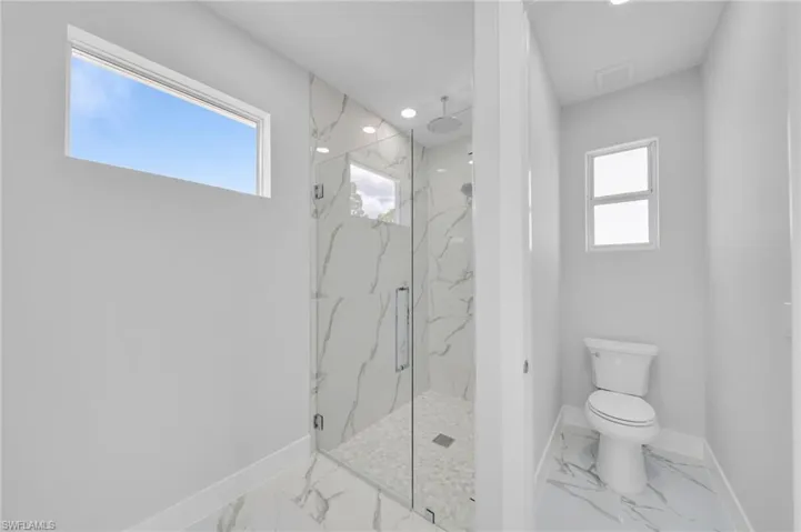 Full bathroom with marble look tiles, baseboards, a marble finish shower, toilet, and recessed lighting