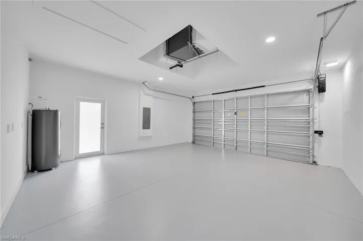 Garage featuring electric panel, water heater, and recessed lighting