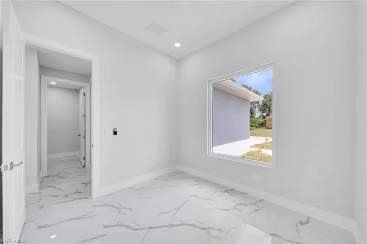 Spare room featuring marble look tiles, baseboards, healthy amount of natural light, and recessed lighting