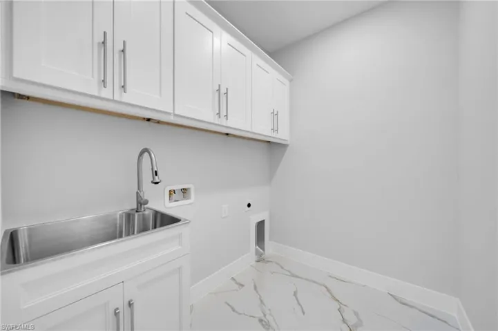 Laundry area with cabinet space, electric dryer hookup, hookup for a washing machine, marble look tile flooring, and baseboards