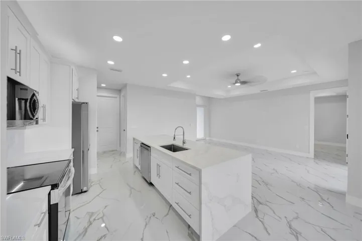 Kitchen with stainless steel appliances, a sink, white cabinetry, recessed lighting, and a ceiling fan
