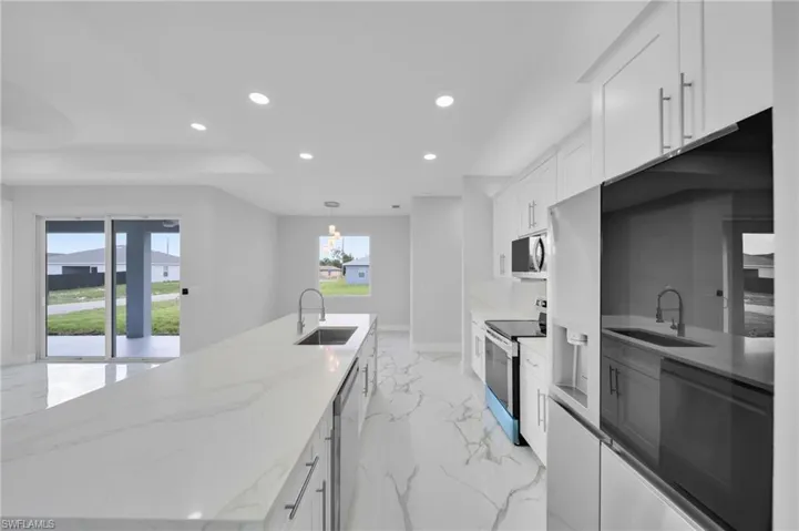 Kitchen with stainless steel appliances, a sink, recessed lighting, light marble finish flooring, and plenty of natural light