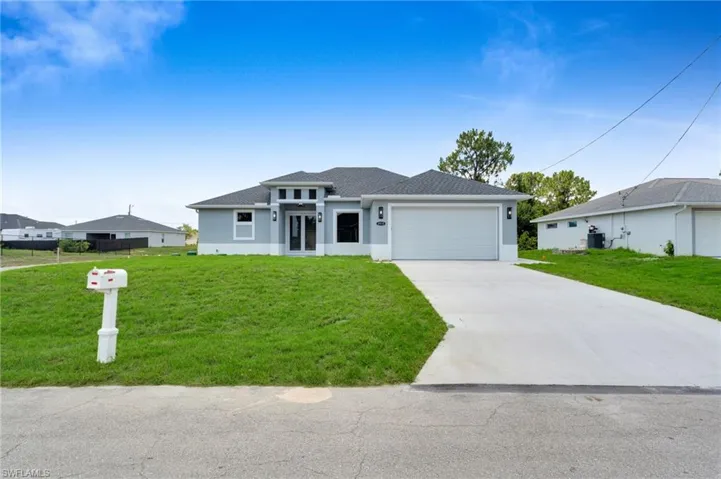 Prairie-style home featuring stucco siding, a garage, concrete driveway, a front yard, and roof with shingles