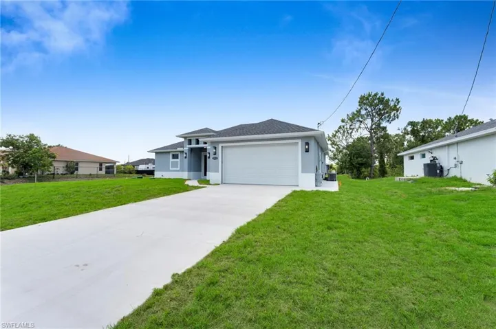 View of front of house with stucco siding, driveway, a garage, a front yard, and central AC