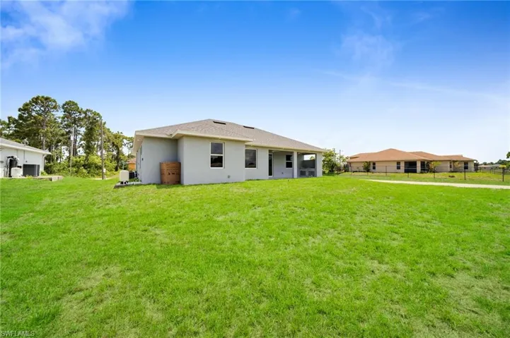 Back of house featuring a yard and stucco siding