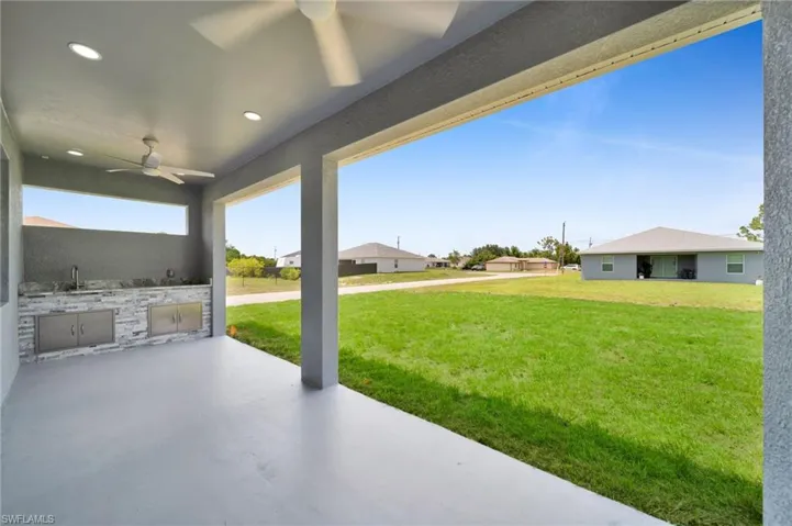 View of patio with an outdoor kitchen, ceiling fan, and a sink