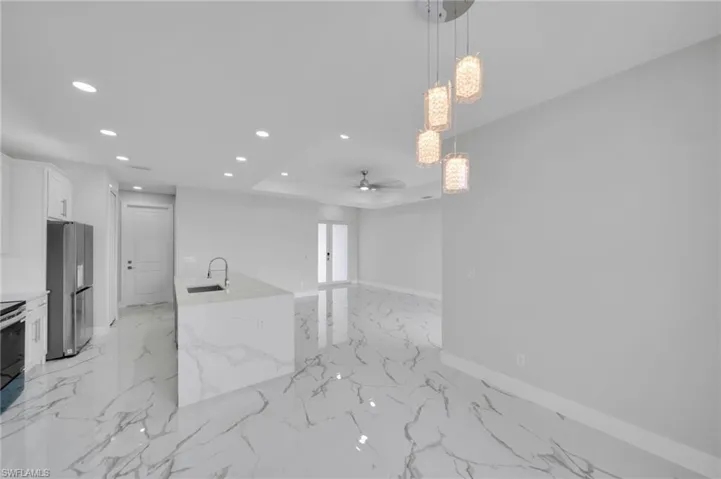 Kitchen featuring freestanding refrigerator, recessed lighting, a ceiling fan, light marble finish flooring, and baseboards
