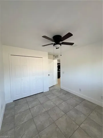 Unfurnished bedroom with ceiling fan, a closet, and light tile patterned floors