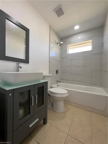 Bathroom with vanity, tub / shower combination, and light tile patterned floors