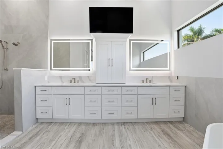 Full bathroom featuring double vanity, tile walls, walk in shower, and light wood-style floors