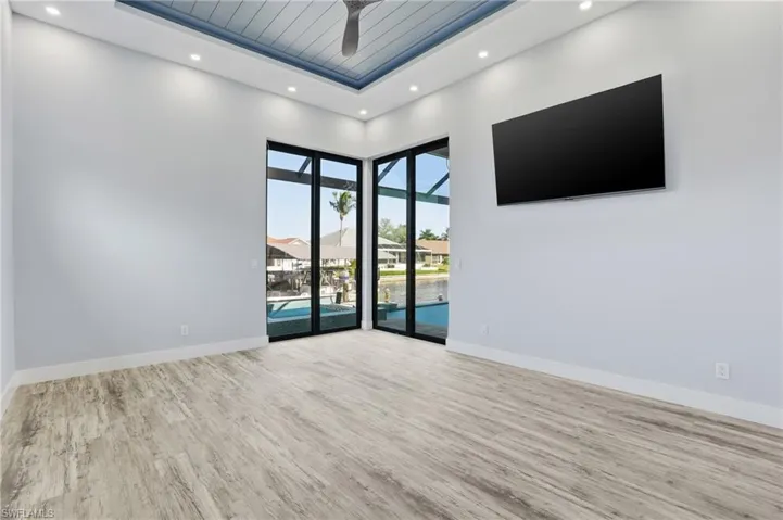 Spare room featuring a high ceiling, a sunroom, wood finished floors, recessed lighting, and ceiling fan