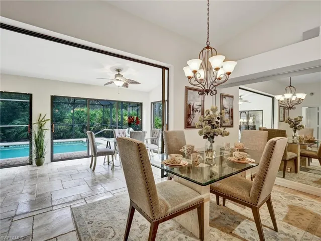 Dining room featuring ceiling fan, stone tile floors, and a chandelier