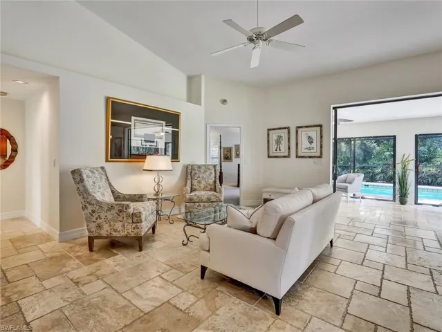 Living area featuring a ceiling fan, lofted ceiling, and stone tile floors