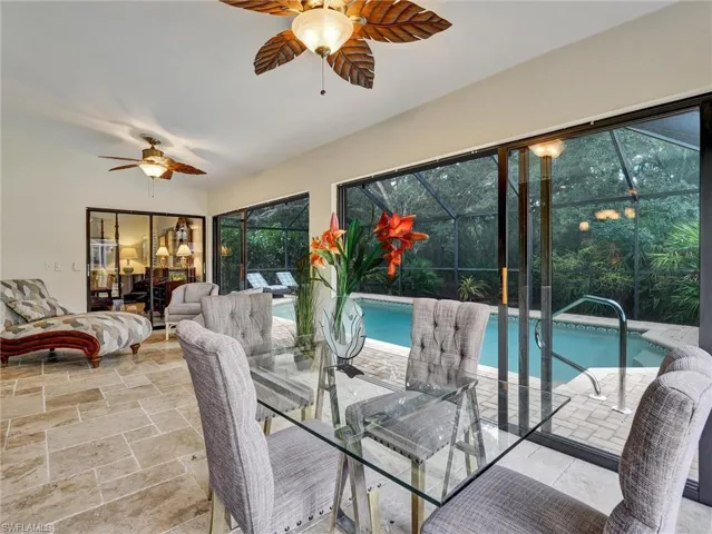 Dining area with a sunroom, stone tile flooring, and ceiling fan