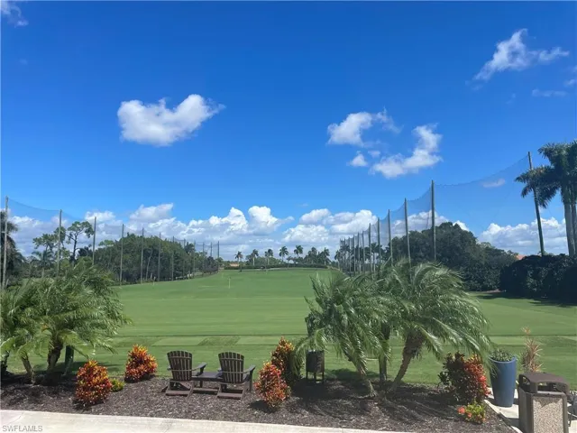 View of community featuring a lawn, golf course view, and view of wooded area
