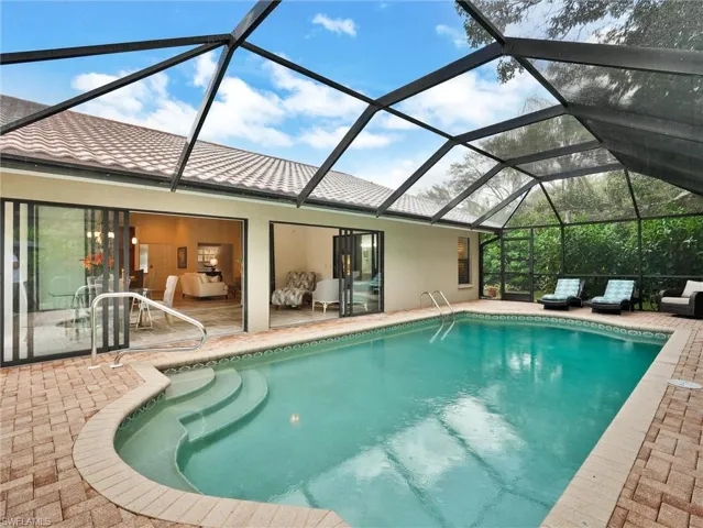 Outdoor pool with a sunroom, a patio area, and glass enclosure