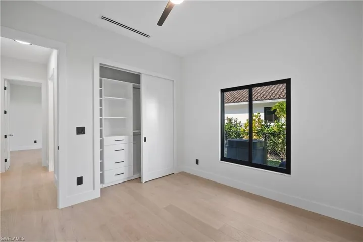 Unfurnished bedroom with light wood-style flooring, ceiling fan, and a closet