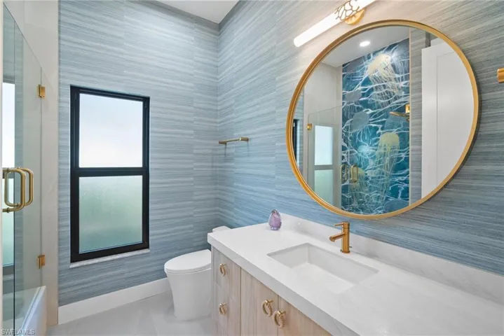 Bathroom with tile walls, vanity, a shower with shower door, and light tile patterned flooring