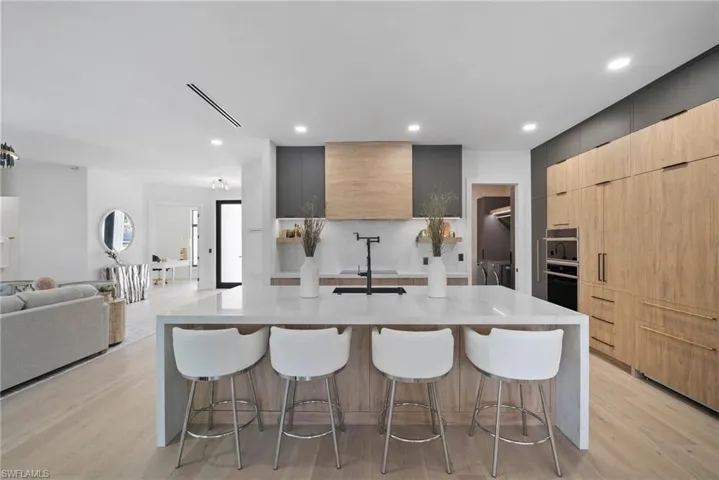 Kitchen with modern cabinets, light stone counters, two tone cabinets, a breakfast bar area, and light wood-style floors