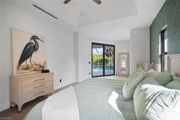 Bedroom featuring access to exterior, wood finished floors, ceiling fan, and a tray ceiling