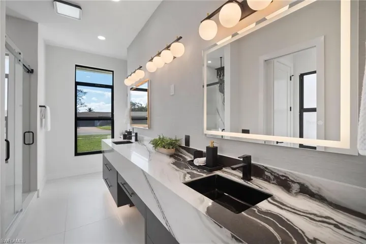 Bathroom featuring a shower stall, double vanity, and light tile patterned flooring