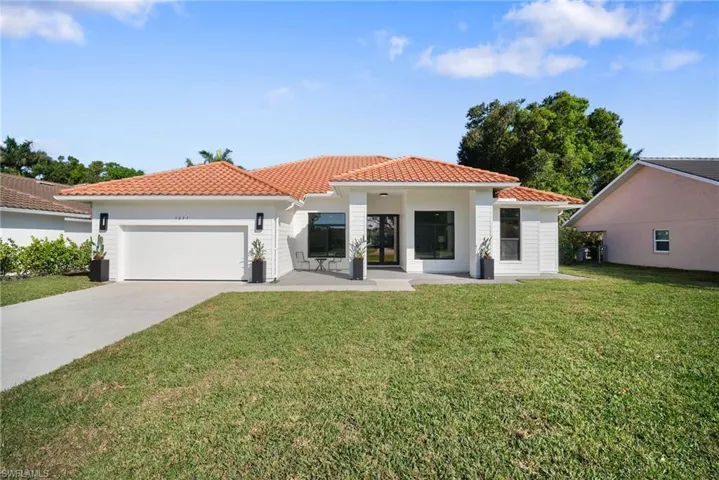 View of front of house featuring a tiled roof, a front yard, driveway, and a garage