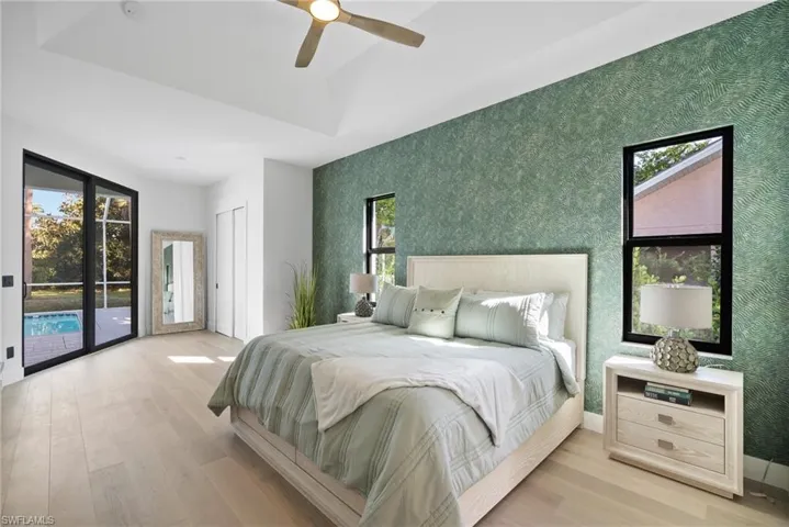 Bedroom with wallpapered walls, light wood finished floors, access to exterior, ceiling fan, and a closet