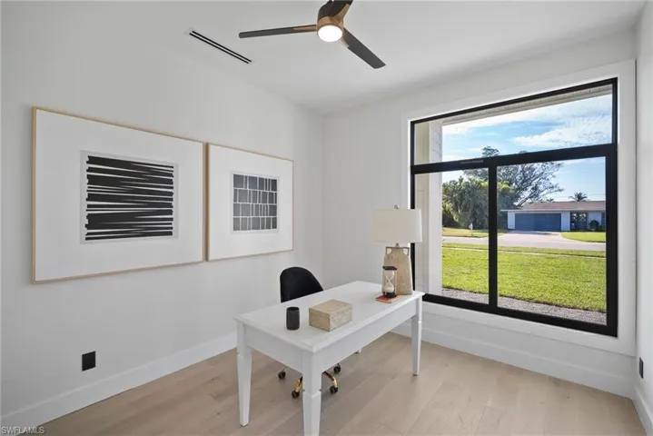Home office with light wood-style flooring and ceiling fan