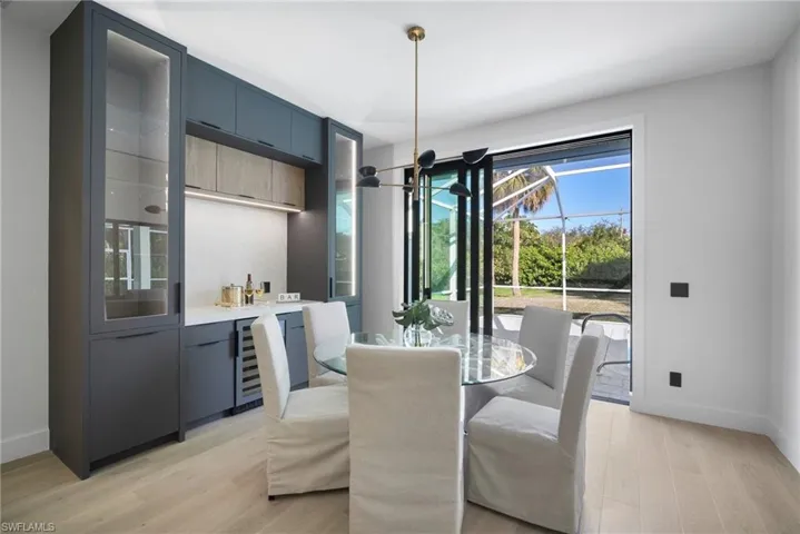 Dining room with a sunroom, light wood-style floors, wine cooler, and bar area
