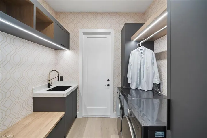 Laundry room featuring light wood-style floors, washing machine and clothes dryer, and wallpapered walls
