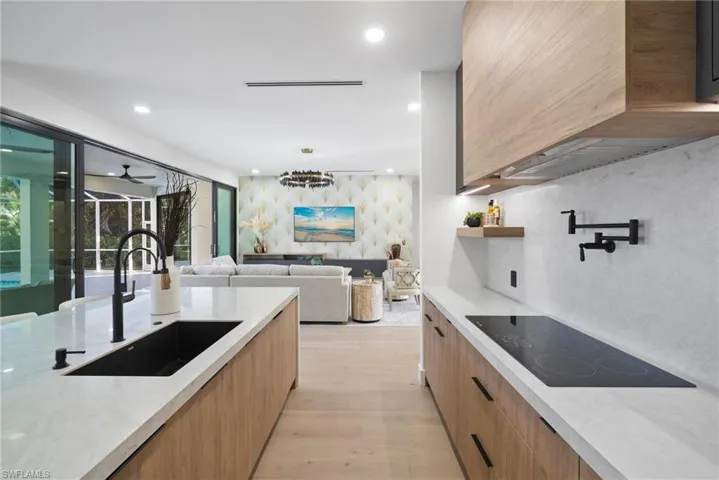 Kitchen with modern cabinets, light stone counters, black electric cooktop, light wood-type flooring, and recessed lighting
