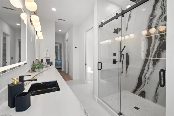 Full bath with a marble finish shower, vanity, ensuite bathroom, and recessed lighting