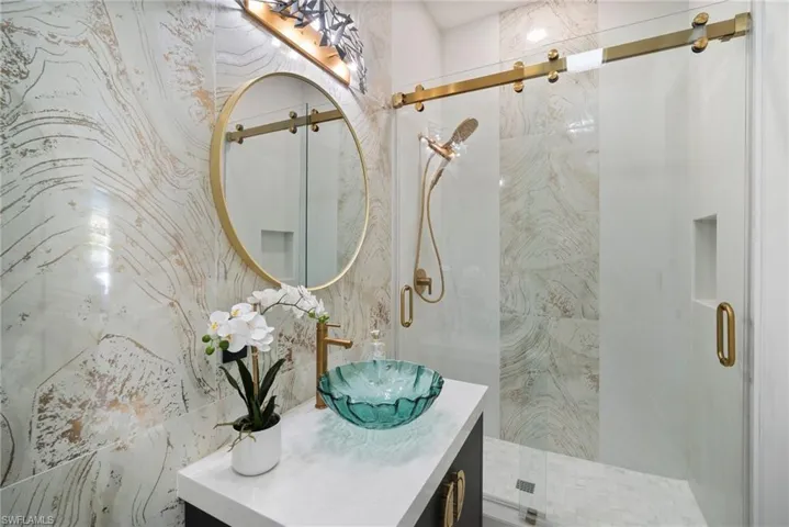 Bathroom featuring vanity and a marble finish shower