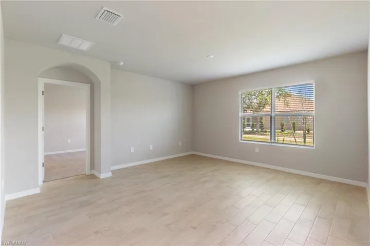 Unfurnished room with arched walkways and light wood-type flooring