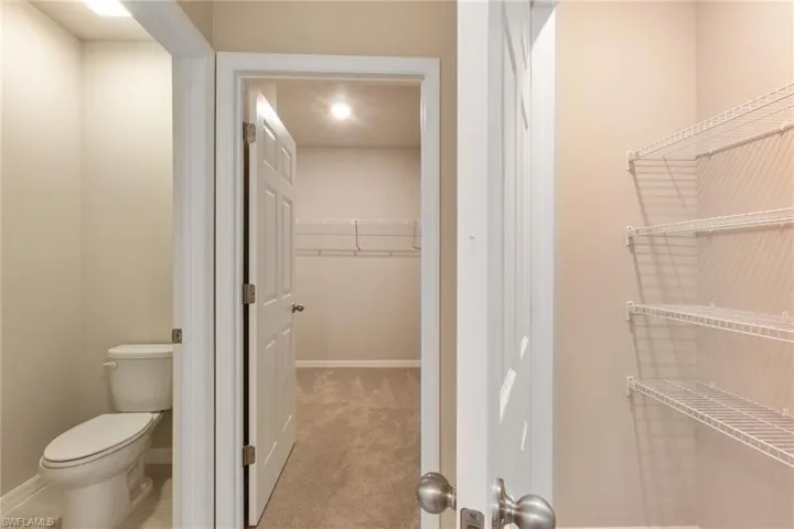 Bathroom featuring a spacious closet and light colored carpet
