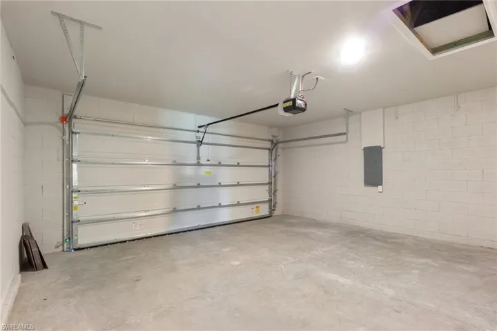 Garage featuring concrete block wall, electric panel, and a garage door opener