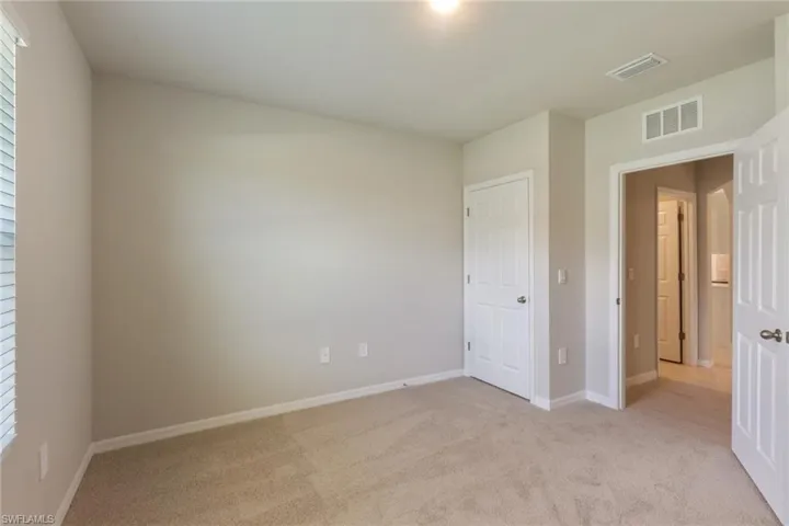 Unfurnished bedroom featuring light carpet and baseboards