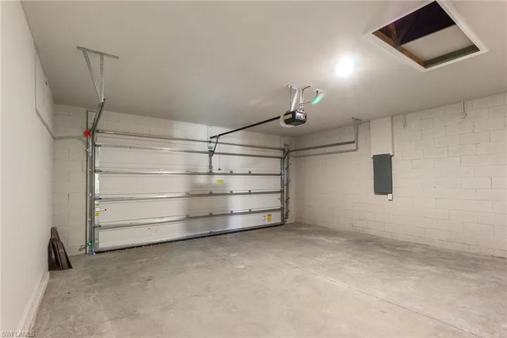 Garage with concrete block wall, electric panel, and a garage door opener