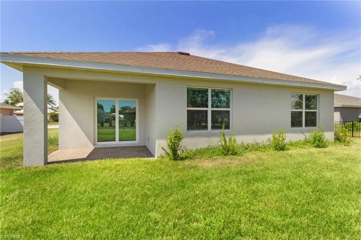 Rear view of property with a shingled roof, stucco siding, and a patio