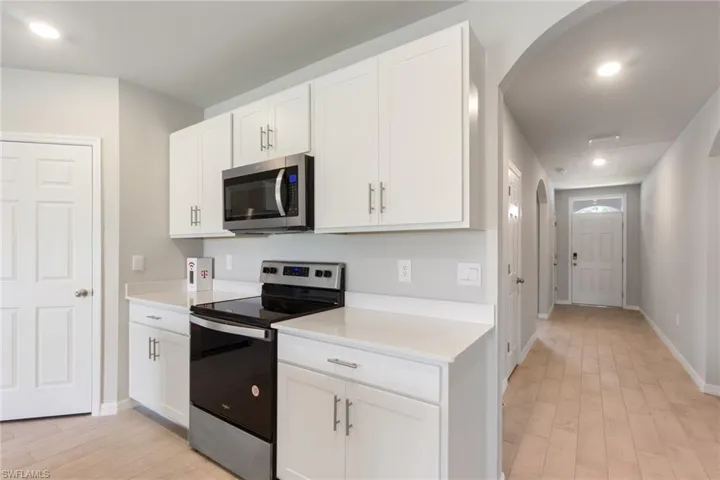 Kitchen with stainless steel appliances, recessed lighting, white cabinets, arched walkways, and light wood-type flooring