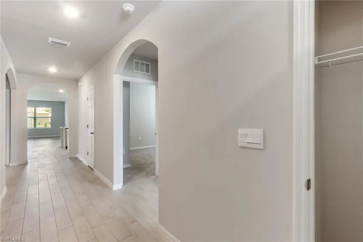 Corridor featuring arched walkways and light wood-style floors