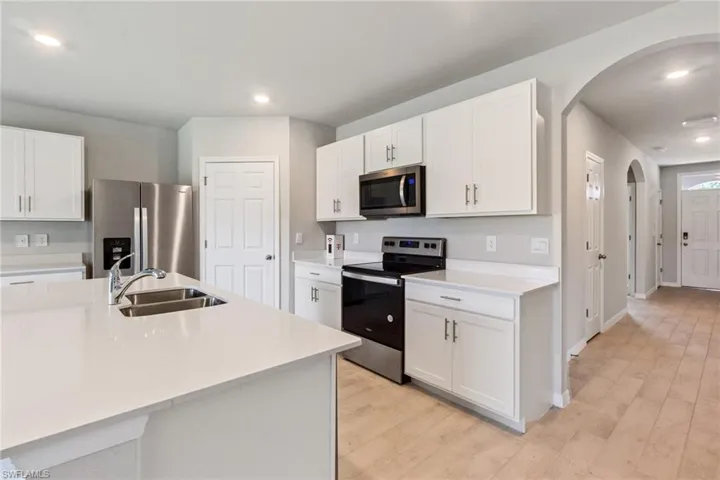 Kitchen with stainless steel appliances, arched walkways, white cabinets, recessed lighting, and light wood-style flooring