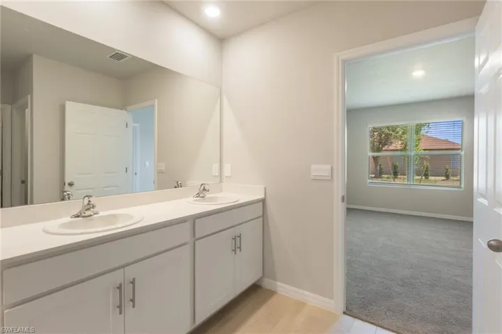 Bathroom featuring double vanity, recessed lighting, and light carpet